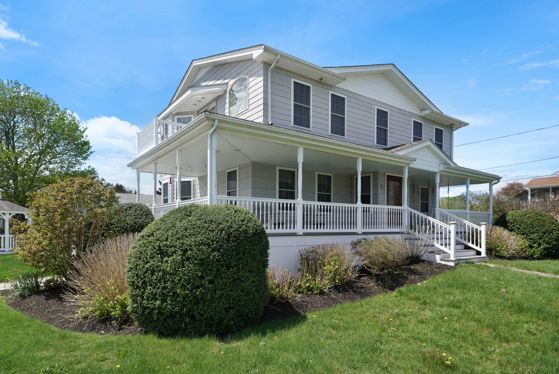 Two-story home with wrap-around porch and large lawn.