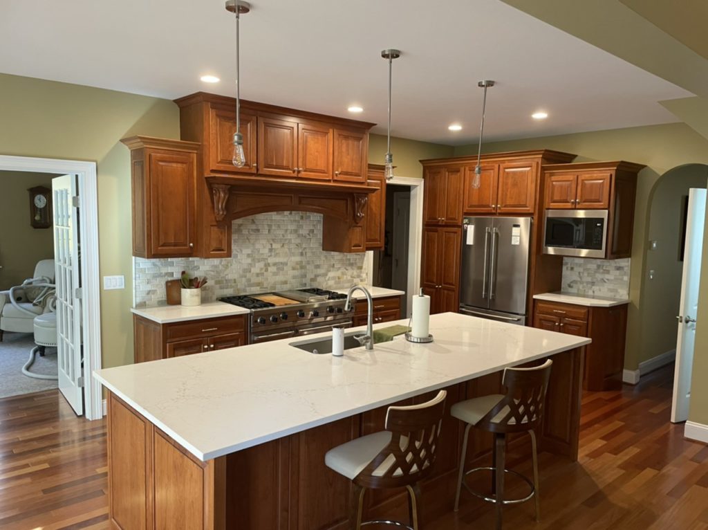 Remodeled kitchen with wood-tone cabinets, white quartz countertop, and large island.