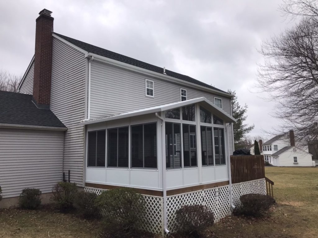 Screened-in porch on back of a home with gray vinyl siding.