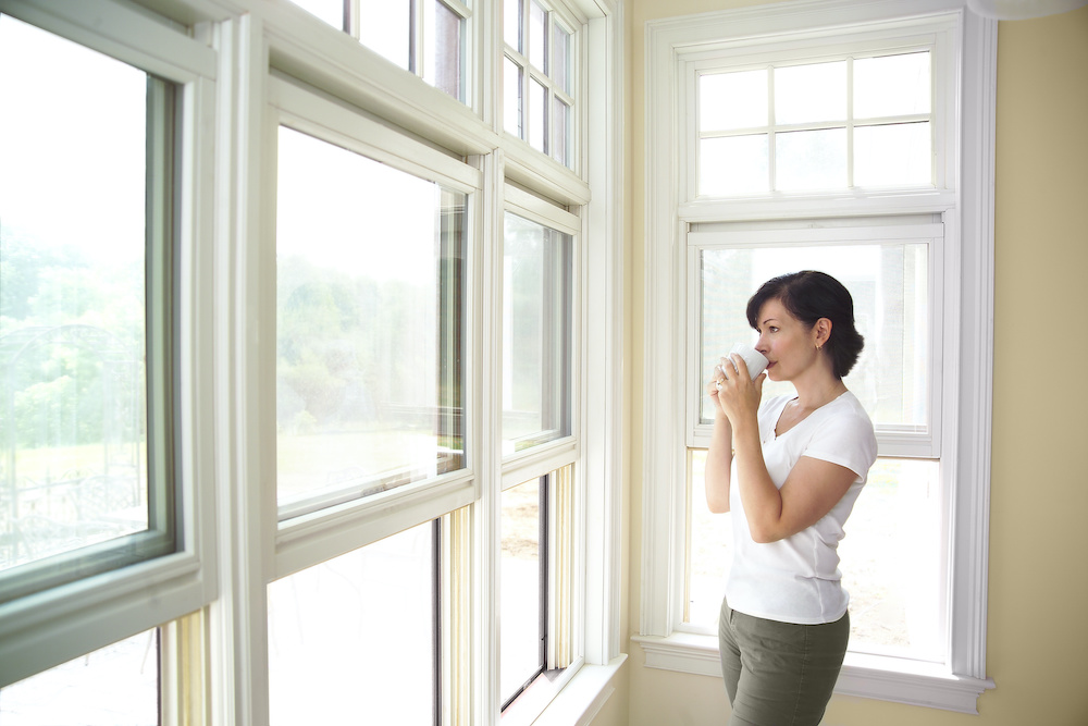 A woman sips coffee and looks out the window.