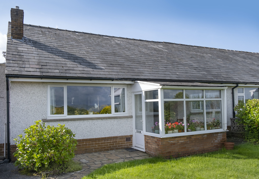 60's bungalow with slate roof, white quartz render and upvc double glazed windows and front porch.