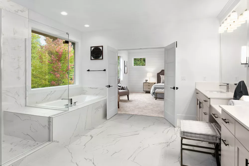 Master bathroom interior in new luxury home with marble floors and wall accents. Shows view of master bedroom