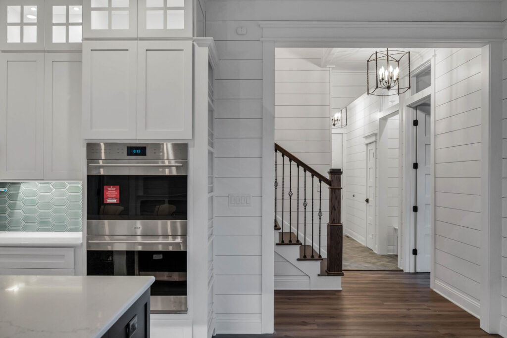 a kitchen with white cabinets and wood floors