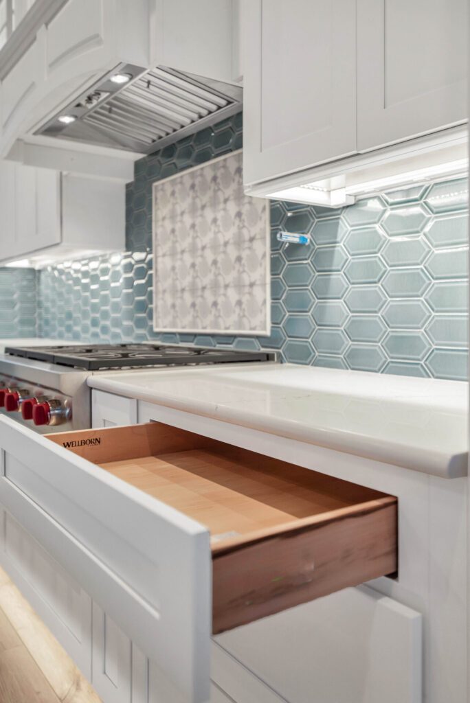 a kitchen with white cabinets and a wooden drawer