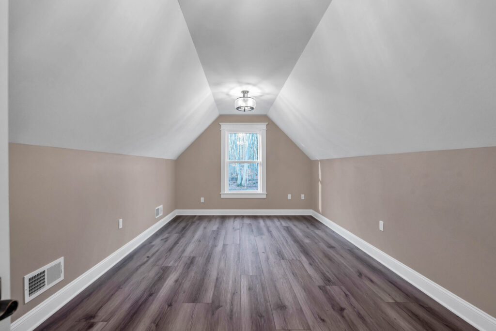an empty room with wood floors and a skylight