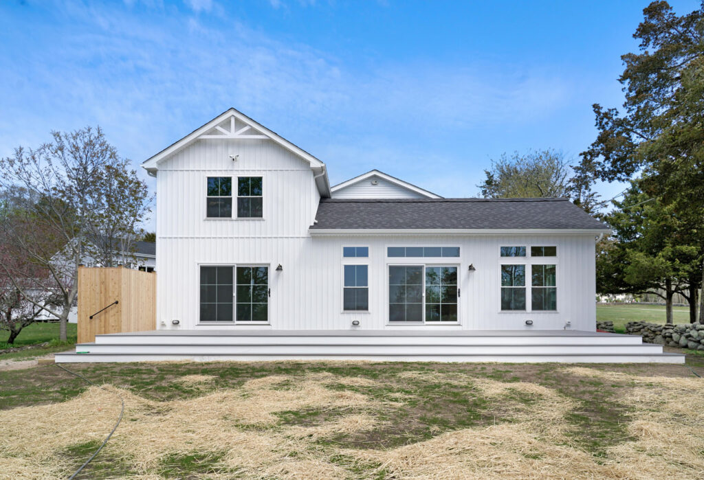 White vinyl siding on two story house with deck and backyard