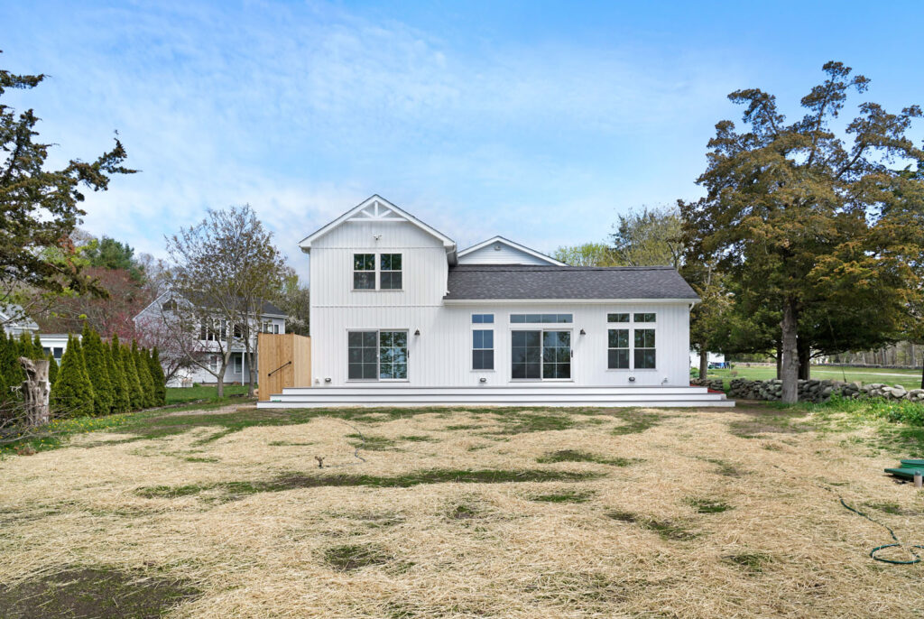 White house with new siding with attached deck and back yard