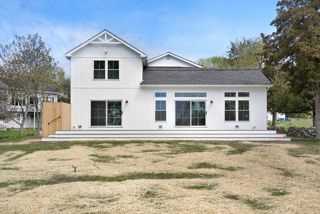 White house with new siding and windows with attached deck and backyard