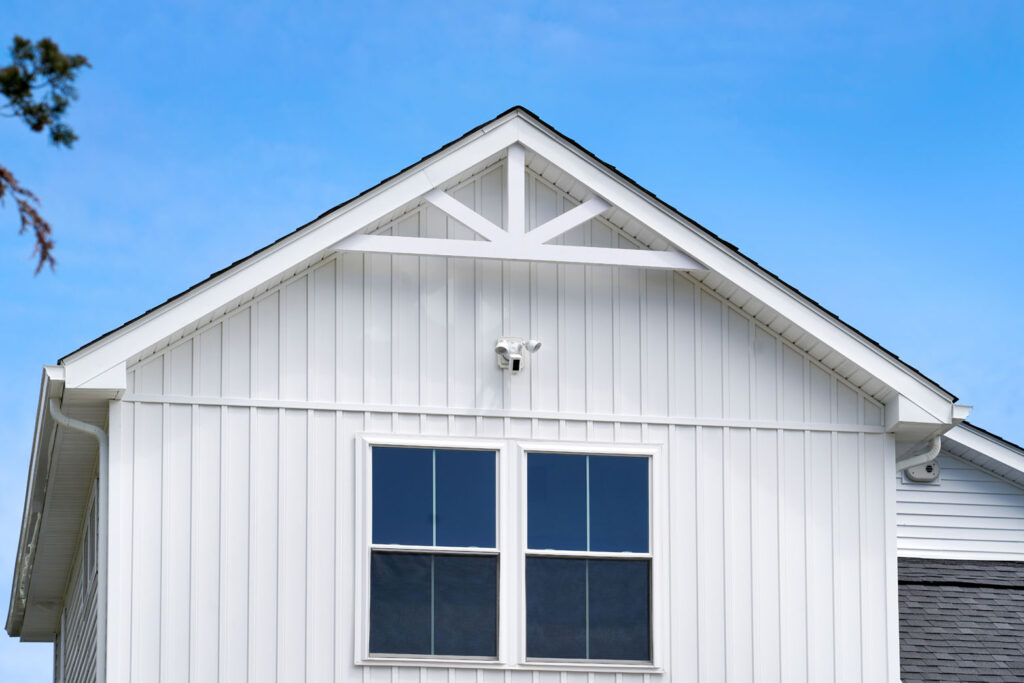 New white vertical siding on house with gable roof and new windows