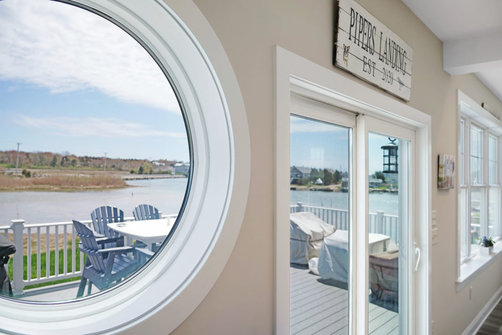 Circular window and sliding glass doors with white trim looking out over lake