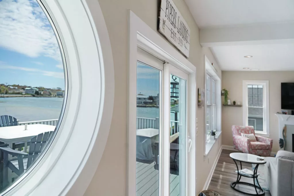 Circular window and sliding glass doors in home looking out over lake