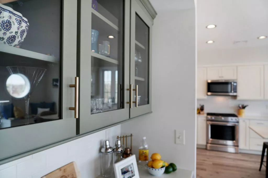 New grey kitchen cabinets with glass inserts, stainless steel stove and hood