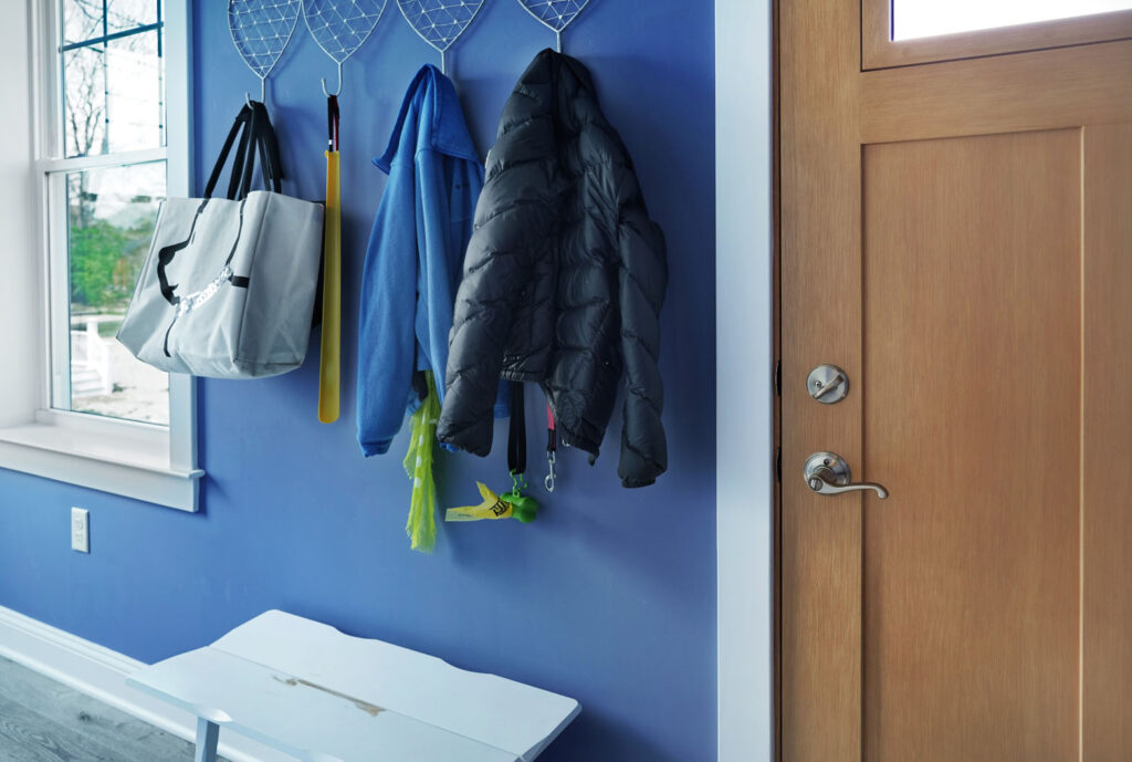 Home with blue wall with bags and coats hanging from wall mounted hooks