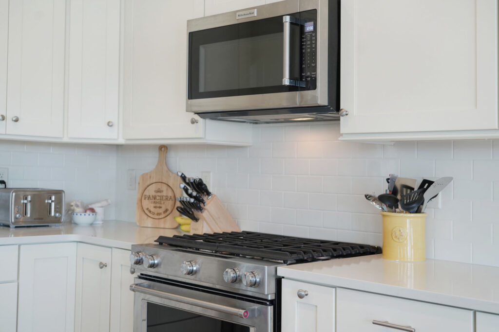 White kitchen with new stainless steel gas stove and hood