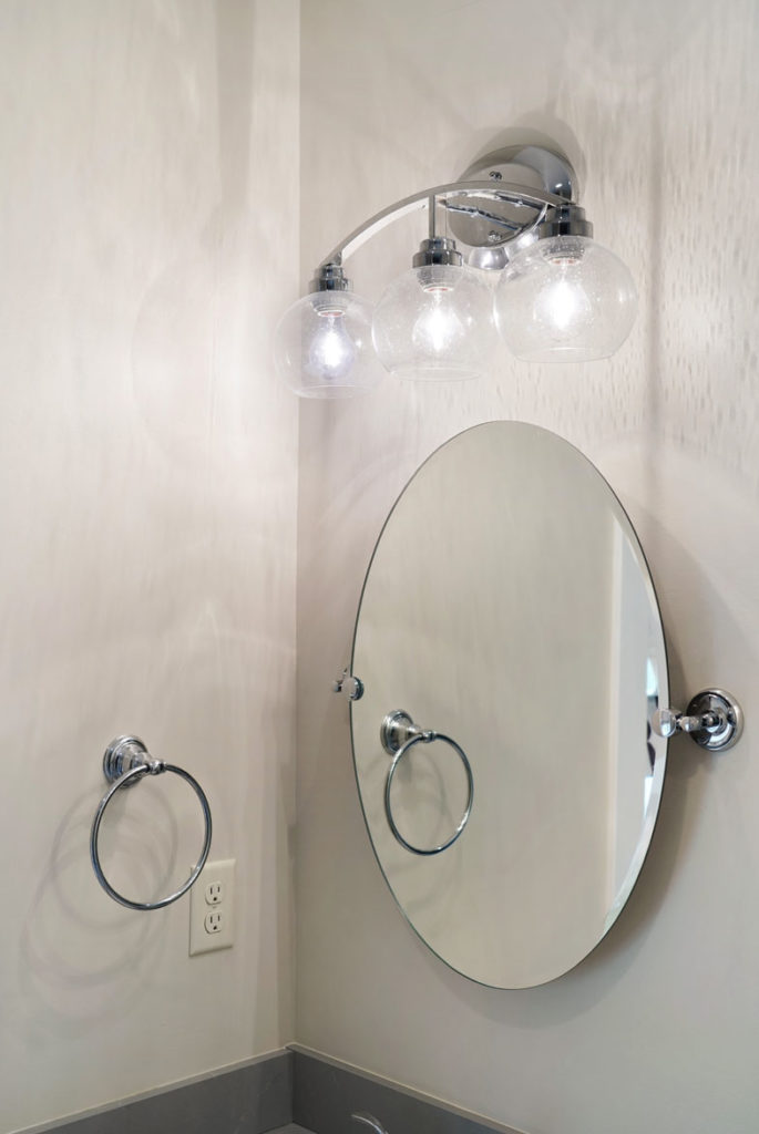 Bathroom with oval mirror and chrome light and towel holder