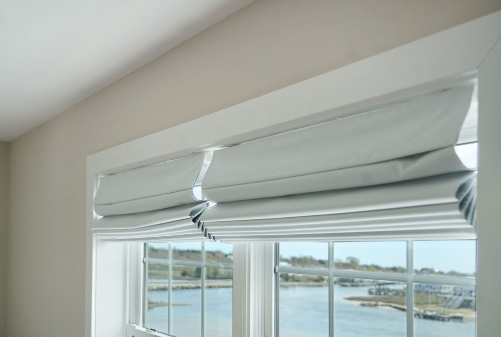 New fabric roll-up blinds over windows looking out over water and shore