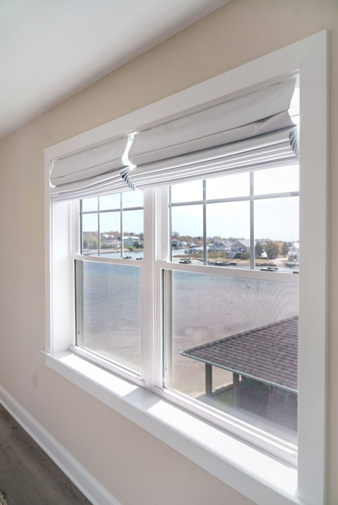 New windows with white trim and fabric roll-up blinds with view of lake