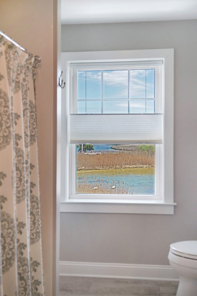New window in bathroom with paper roll-up privacy shade with lake view
