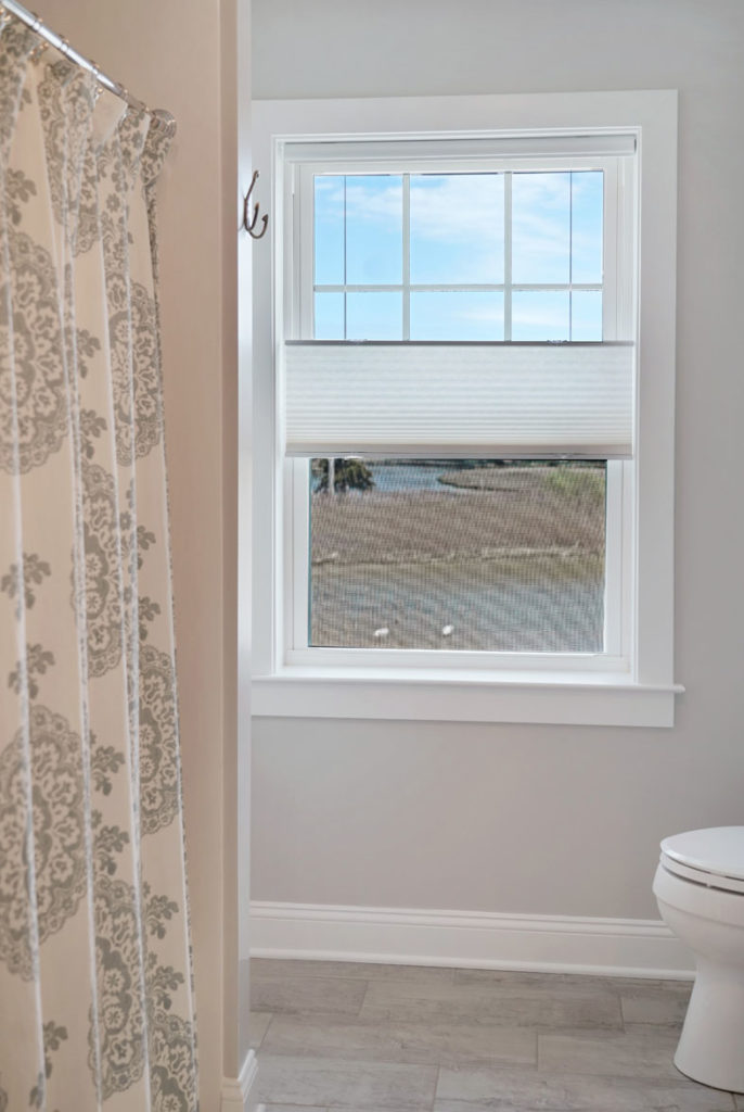 New window in bathroom with paper roll-up privacy shade with screen