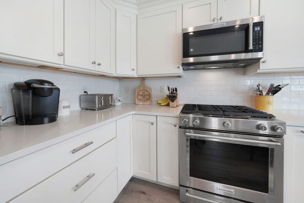 Kitchen with new white cabinets and stainless steel gas stove and microwave hood