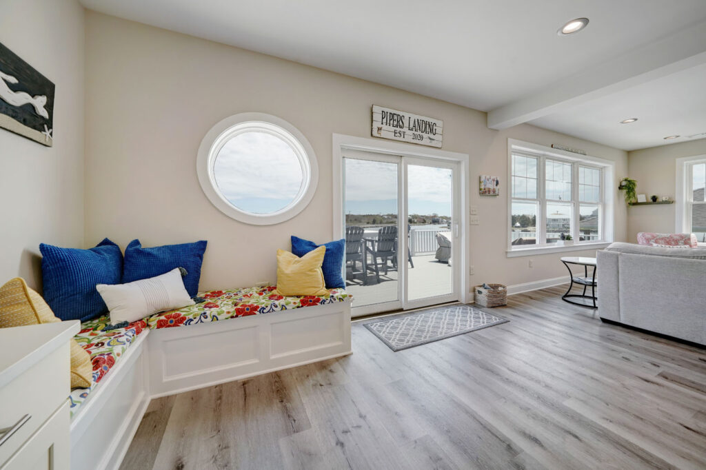 Home with corner bench seat, grey wood floor, and sliding glass doors with view of deck