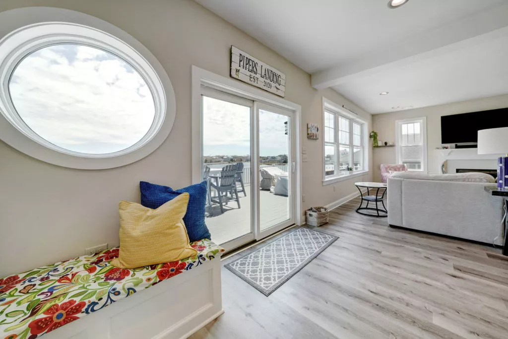 Home with grey wood floor, sliding glass doors, circular window and view of deck and lake