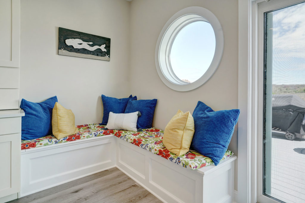 an upholstered seating nook with a port hole-style window