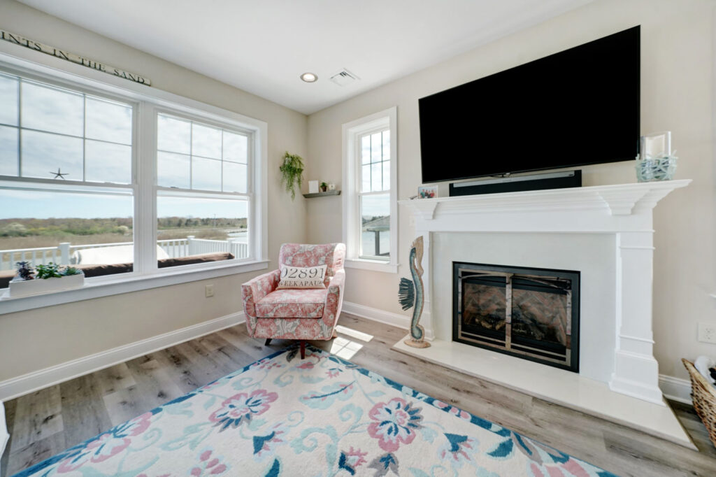 a living room with a fireplace, television and large windows