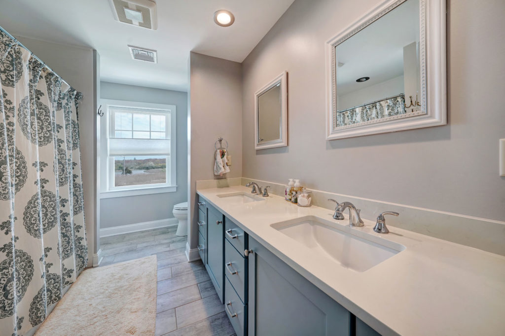a bathroom with double sinks and grey cabinets