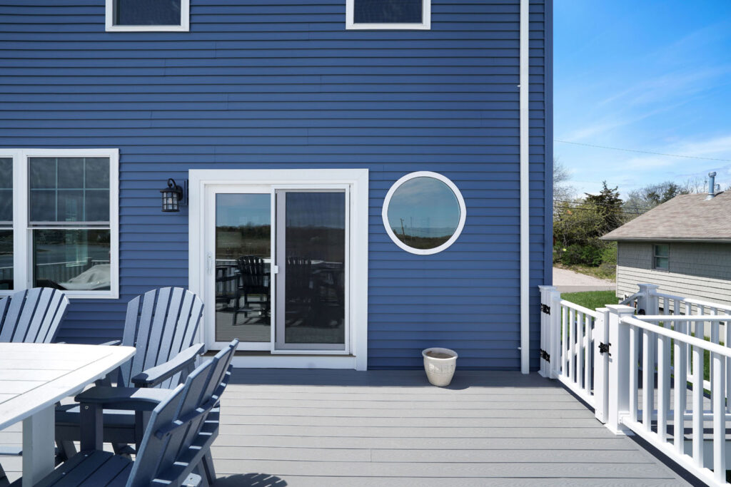 A blue house with a white table and chairs featuring a deck built by Fidero & Sons in Meriden, CT.