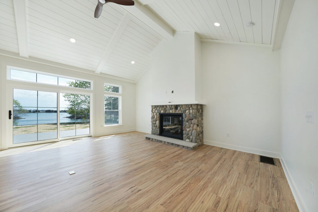 Living room with vaulted ceilings, light wooden flooring, and a stone fireplace.