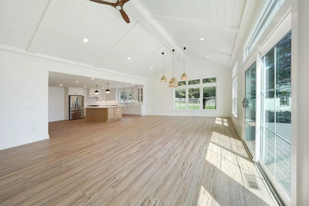 Large living area inside home with sliding glass doors. Open conecept kitchen area in background.