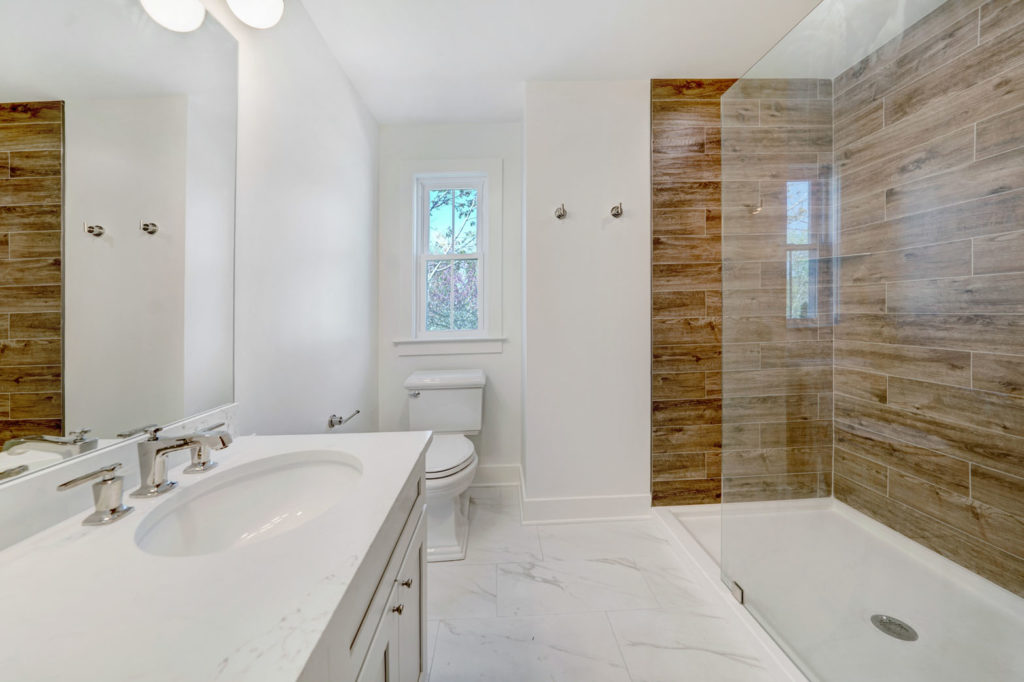 Modern bathroom with white marble counters and flooring and a frameless glass shower.