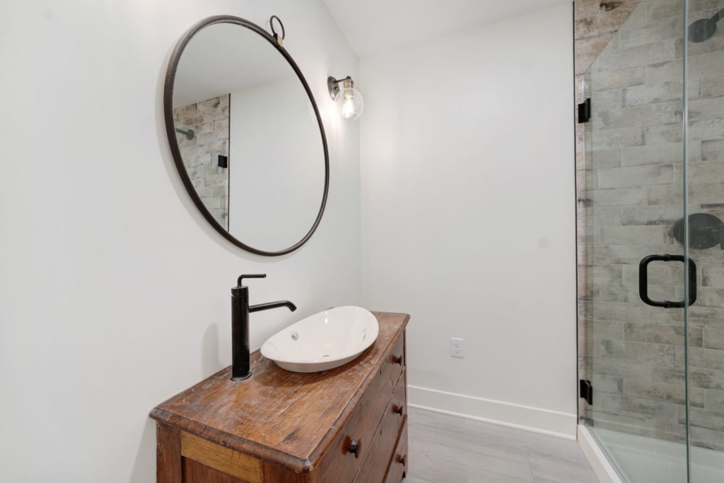 Bathroom with an antique wooden vanity and a frameless glass shower.