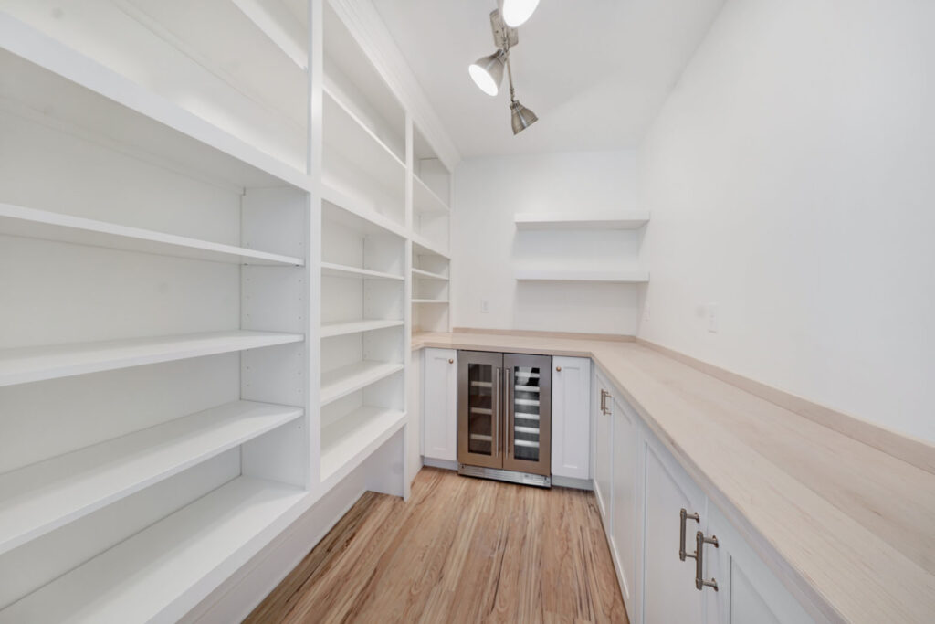 A pantry with built-in shelves, cabinetry, and a wine fridge.