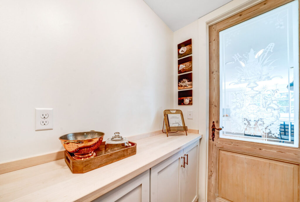 A pantry area inside of a residential home with a wooden & glass door.