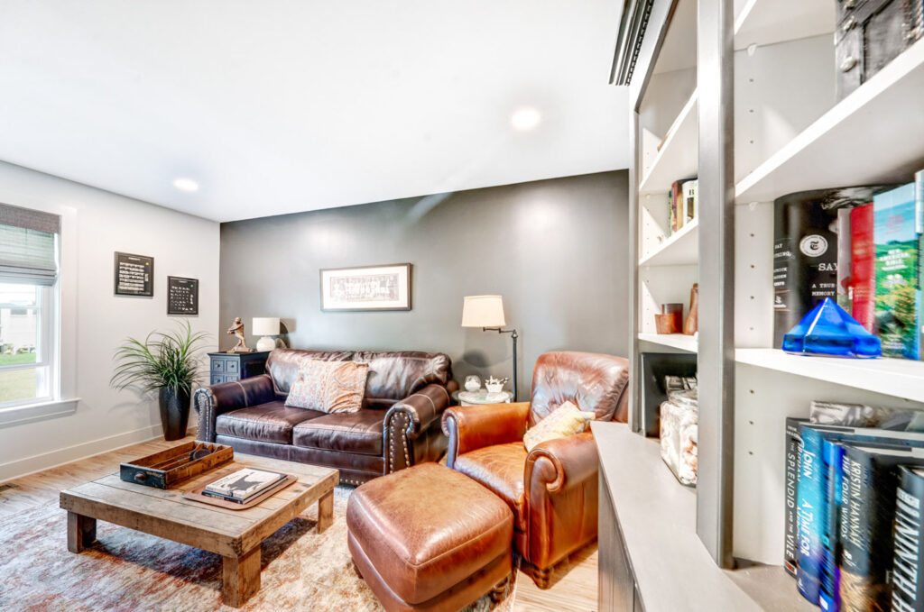 Bookcase inside of study area of home, with comfortable leather sofa and chairs and coffee table.