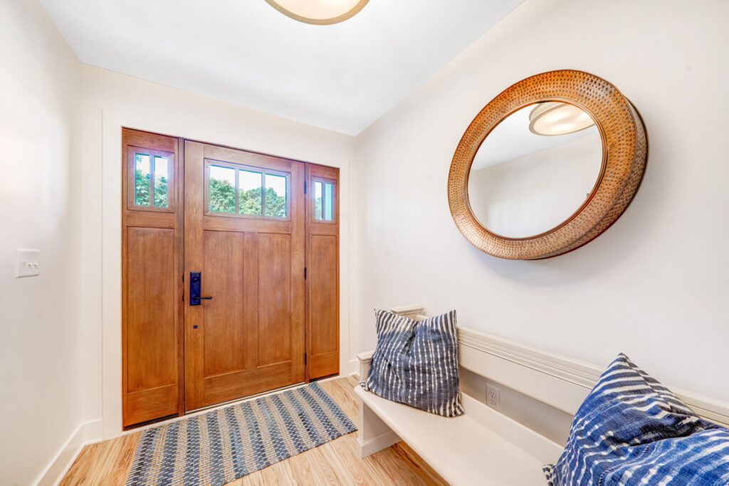 An entryway with a large wooden door and a bench with decorative pillows.