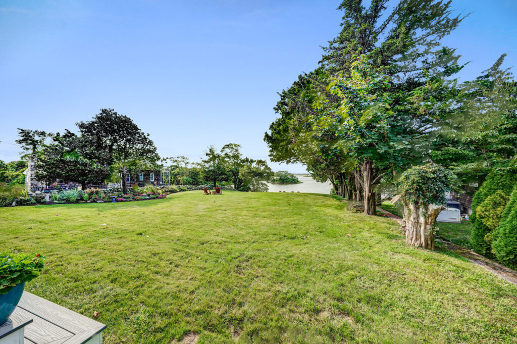 Large backyard area with trees, grass and firepit.