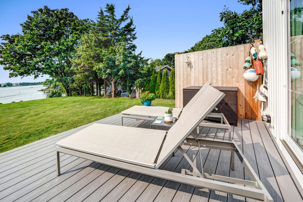 Sun lounge chairs on wooden back deck overlooking grassy yard.