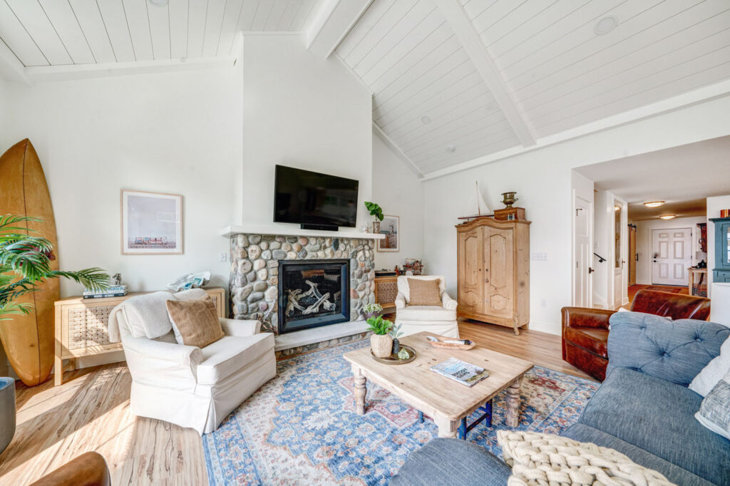 Cosy living area inside home with mounted TV above fireplace and chairs & sofa for relaxing.