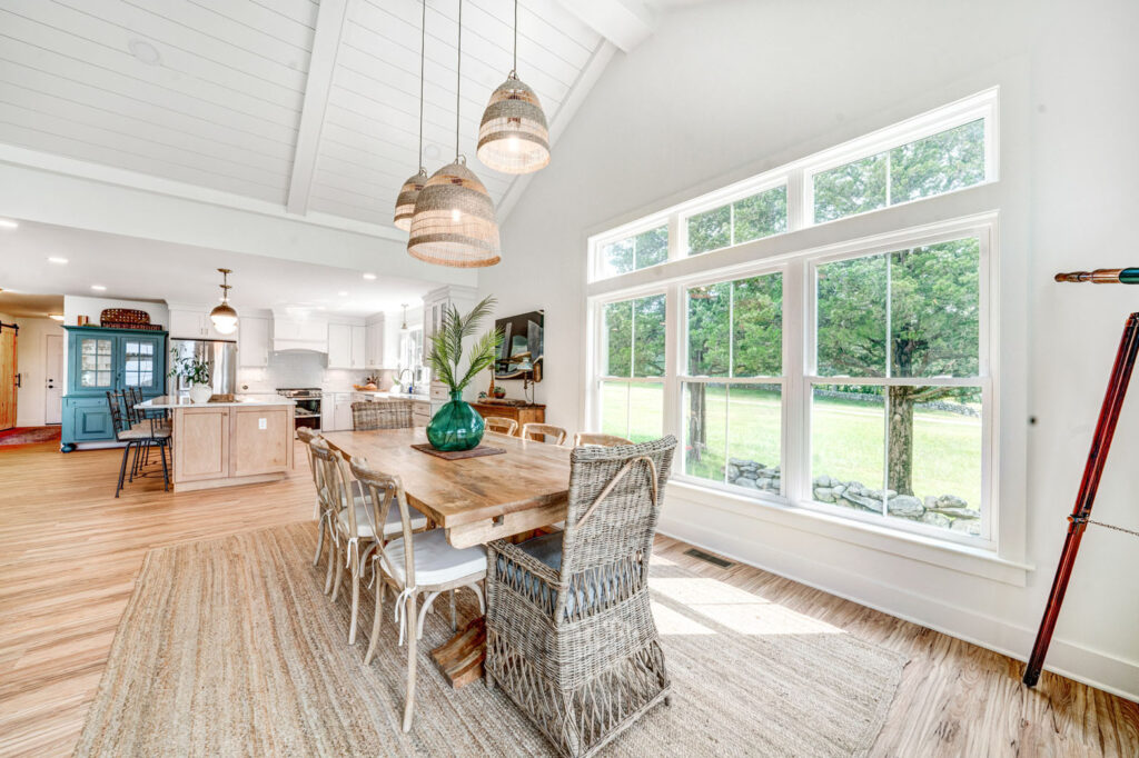 Dining room table and chairs beside large windows in home.