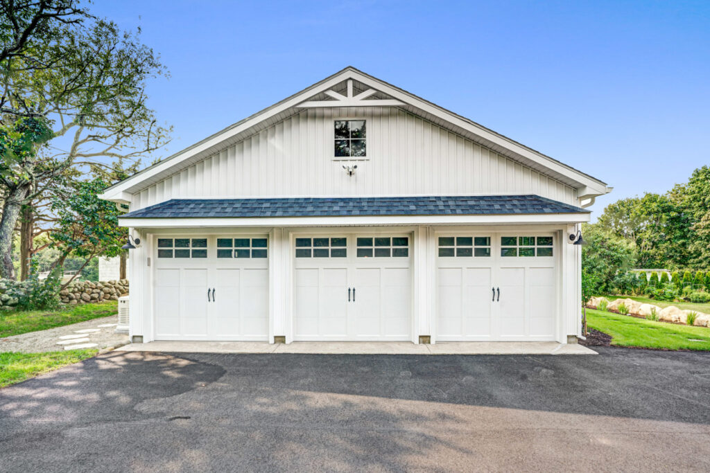 White, stand-alone residential garage with three garage doors.