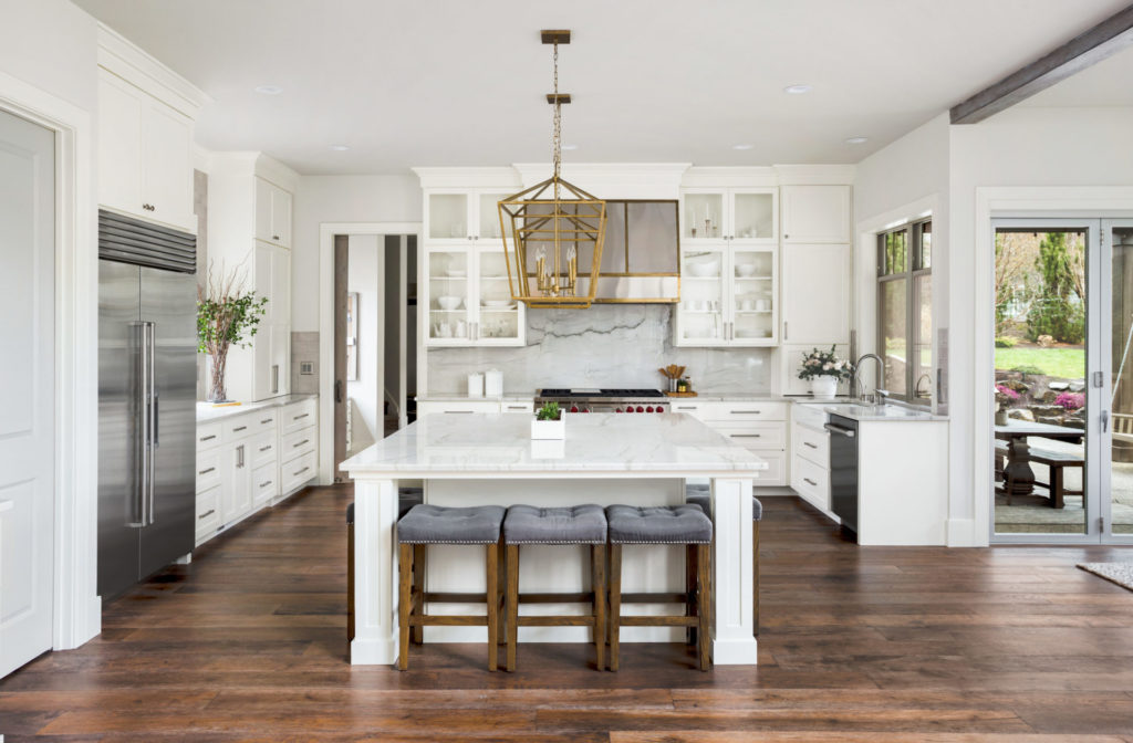 Modern kitchen with white cabinets, marble countertops, and stainless steel appliances.