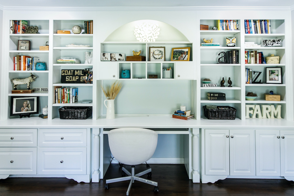 White built-in bookshelves surrounding a desk with white office chair